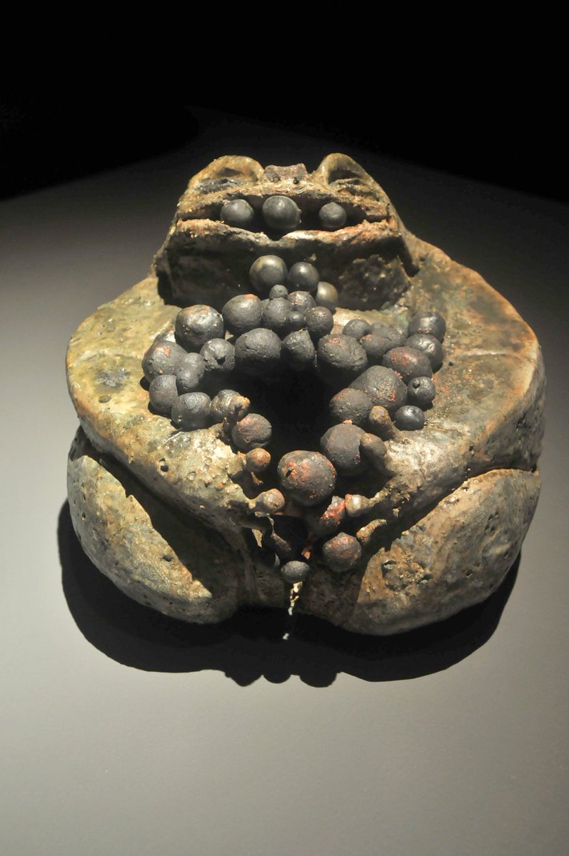 Primer plano de un artefacto antiguo de piedra erosionada con formaciones redondeadas en patrón circular, en tonos tierra y gris